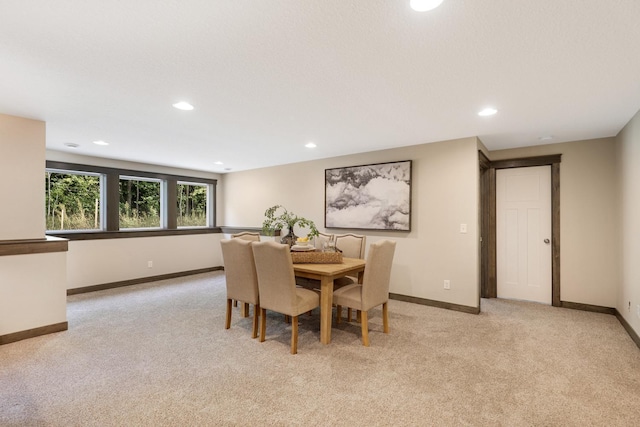 dining space with a textured ceiling and light colored carpet