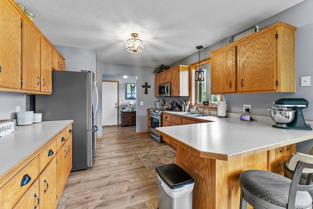 7702 County Road 5 NE, North Branch, MN 55056 - kitchen with stainless steel appliances, light wood-style floors, light countertops, a breakfast bar area, and a textured ceiling