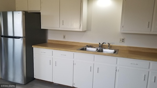 kitchen featuring white cabinets, stainless steel refrigerator, and sink