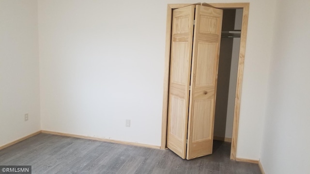 unfurnished bedroom with a closet and dark hardwood / wood-style flooring