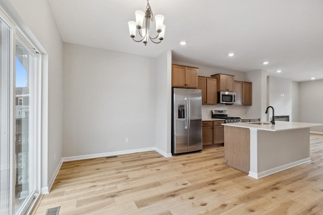 kitchen featuring light wood-type flooring, hanging light fixtures, appliances with stainless steel finishes, and an inviting chandelier