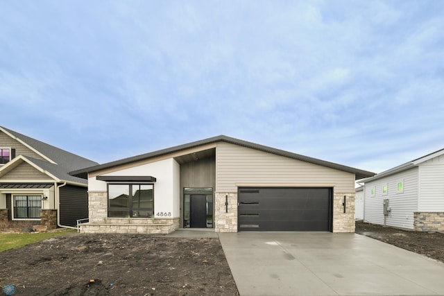 view of front of house featuring an attached garage, concrete driveway, and stone siding