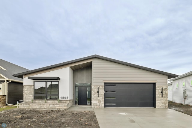 contemporary house featuring a garage, driveway, and stone siding