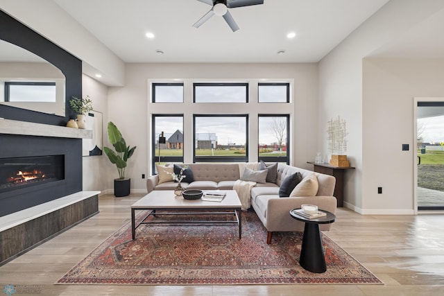 living area featuring light wood-style floors, recessed lighting, and a glass covered fireplace