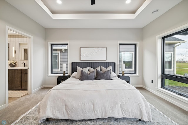 bedroom featuring a sink, a raised ceiling, and light carpet