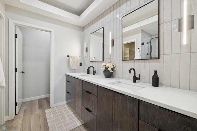 full bath with wood finished floors, double vanity, a sink, and tasteful backsplash