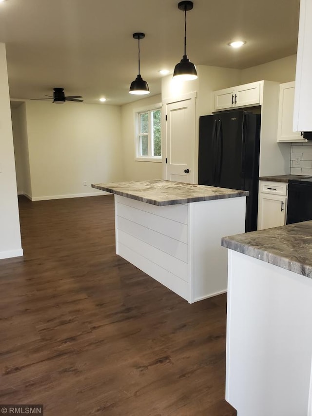 kitchen featuring black fridge, dark hardwood / wood-style floors, decorative light fixtures, decorative backsplash, and white cabinets