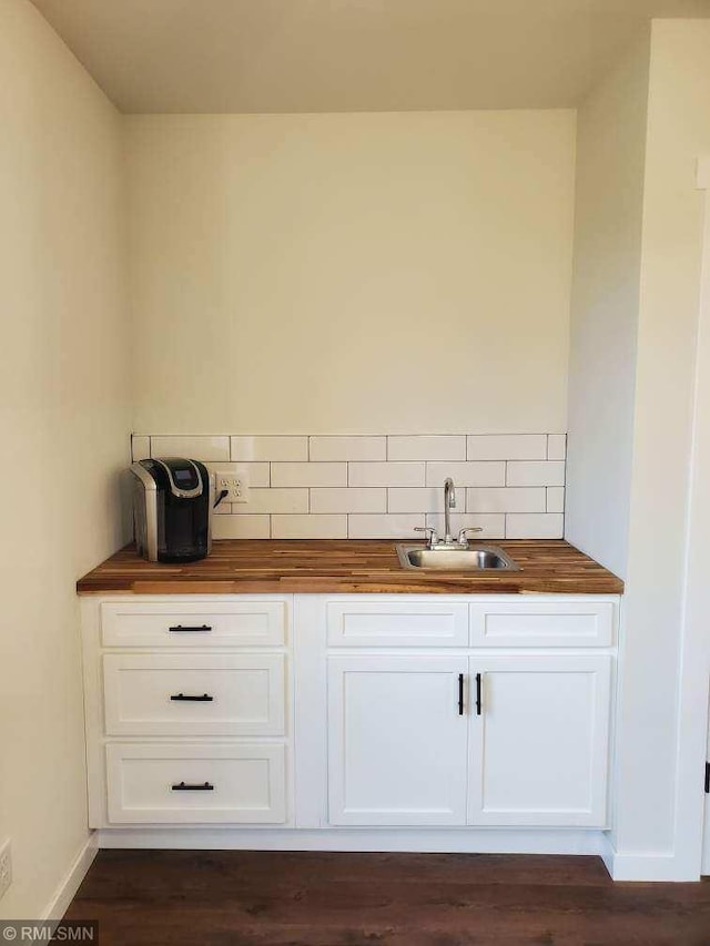 bar featuring sink, tasteful backsplash, dark hardwood / wood-style floors, butcher block countertops, and white cabinets