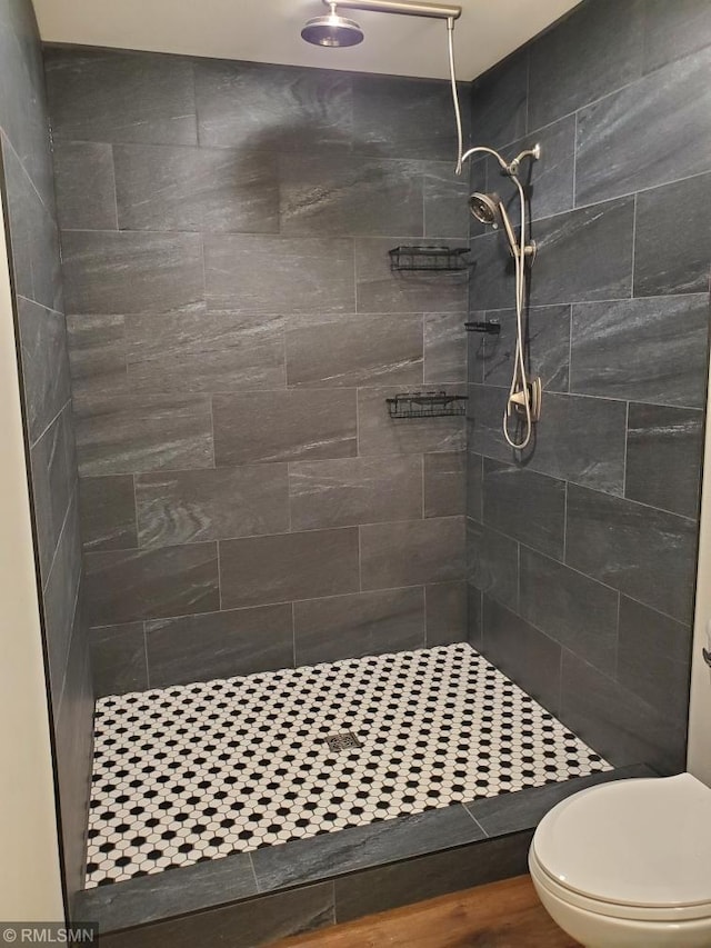 bathroom featuring tiled shower, wood-type flooring, and toilet