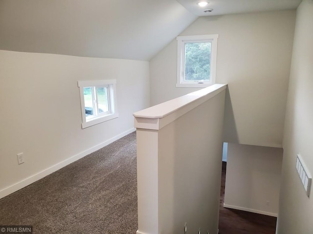 bonus room featuring dark carpet, plenty of natural light, and lofted ceiling