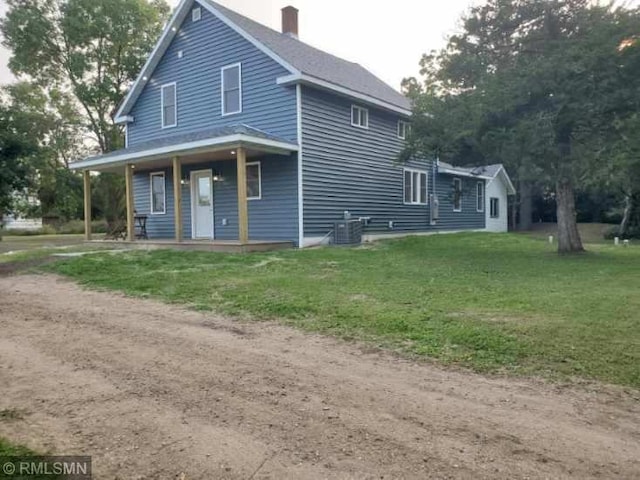 view of front facade featuring a porch, central AC, and a front lawn