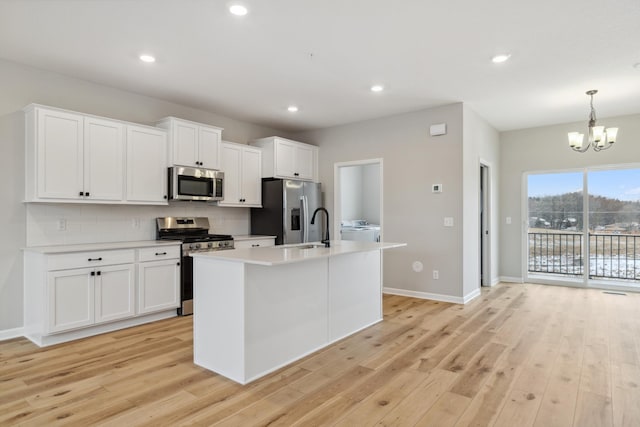 kitchen featuring stainless steel appliances, a chandelier, washer / dryer, white cabinets, and light wood-type flooring