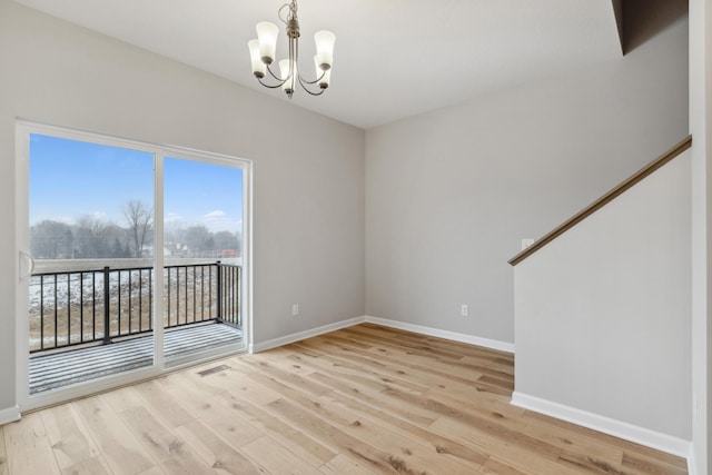 empty room featuring light hardwood / wood-style flooring and an inviting chandelier