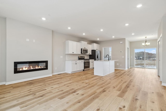 kitchen featuring pendant lighting, sink, light wood-type flooring, appliances with stainless steel finishes, and white cabinetry