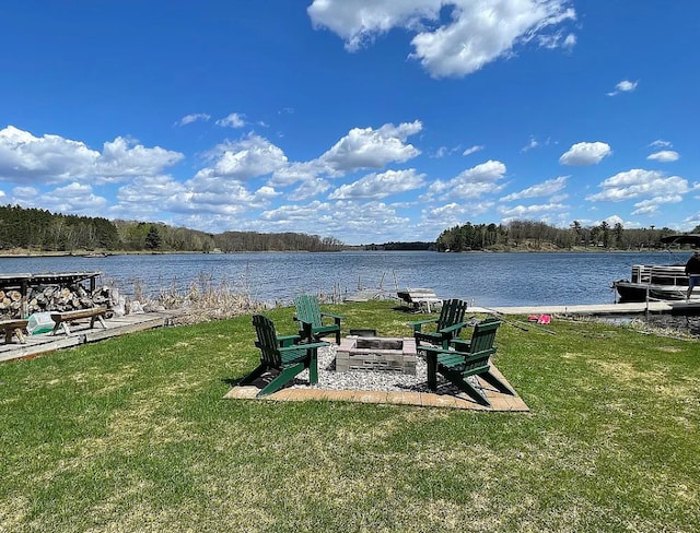 view of dock with a water view, a yard, and an outdoor fire pit