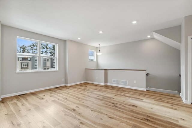 spare room with light hardwood / wood-style flooring and lofted ceiling