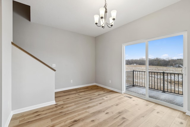 empty room with light hardwood / wood-style flooring and a chandelier