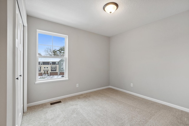 empty room with carpet and a textured ceiling