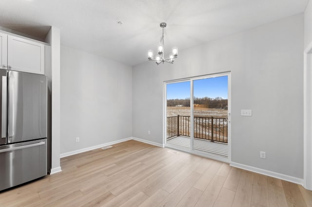 unfurnished dining area featuring light hardwood / wood-style flooring and a notable chandelier