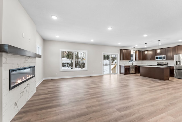 unfurnished living room with sink, light hardwood / wood-style flooring, and a tiled fireplace