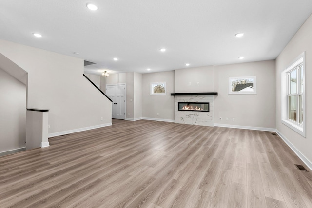 unfurnished living room featuring light hardwood / wood-style flooring and a high end fireplace