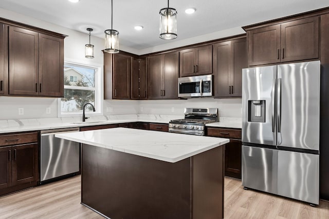 kitchen with sink, stainless steel appliances, pendant lighting, dark brown cabinets, and a kitchen island