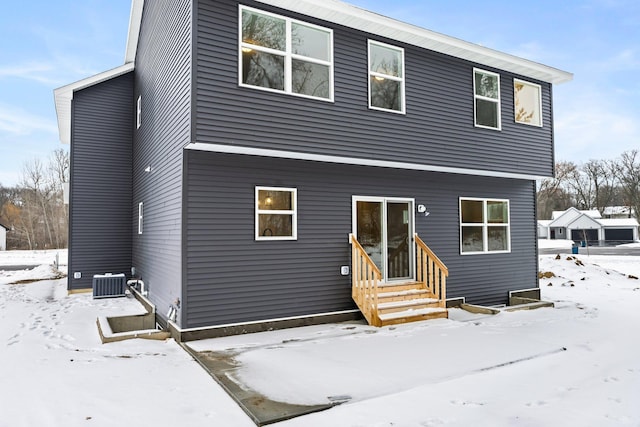 snow covered rear of property featuring central air condition unit