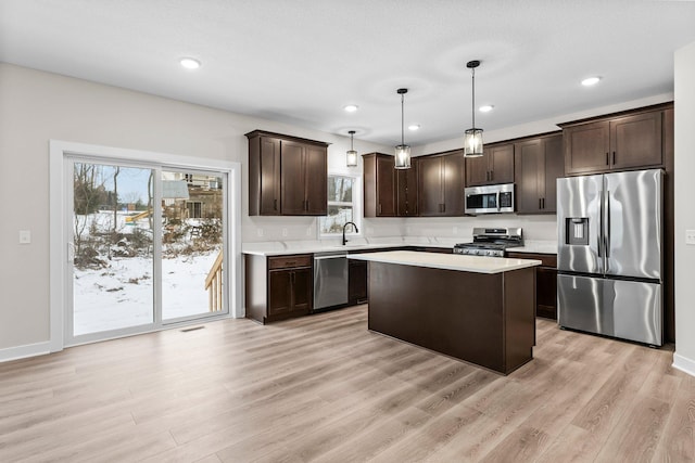 kitchen featuring dark brown cabinets, appliances with stainless steel finishes, light countertops, light wood finished floors, and plenty of natural light