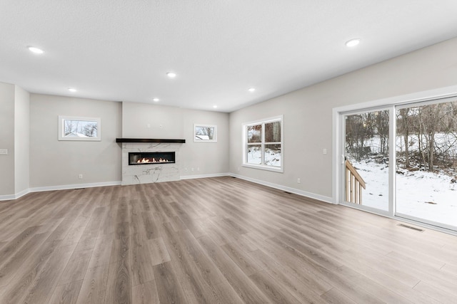 unfurnished living room with recessed lighting, visible vents, wood finished floors, and a high end fireplace