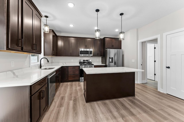 kitchen with dark brown cabinetry, a kitchen island, a sink, appliances with stainless steel finishes, and light wood-type flooring