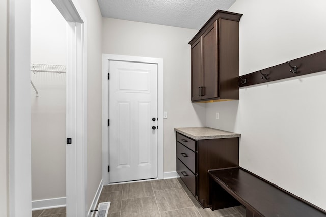 mudroom featuring baseboards, visible vents, and a textured ceiling