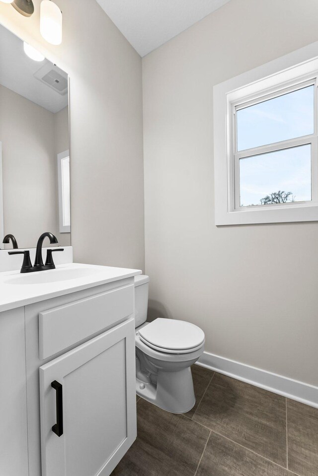 bathroom featuring visible vents, vanity, toilet, and baseboards