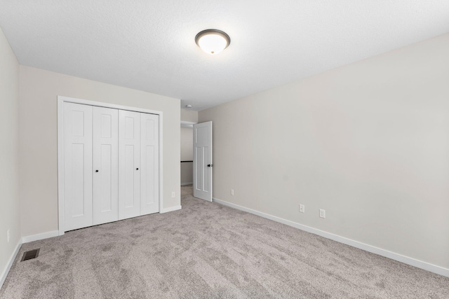 unfurnished bedroom featuring baseboards, a closet, visible vents, and carpet flooring