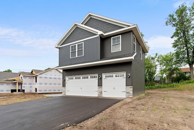 19498 Carson Ct NW, Elk River, MN 55330 - view of front of property with asphalt driveway, a garage, and stone siding