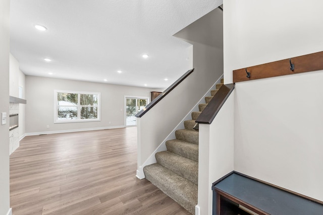 19498 Carson Ct NW, Elk River, MN 55330 - stairs featuring wood finished floors, recessed lighting, and a glass covered fireplace