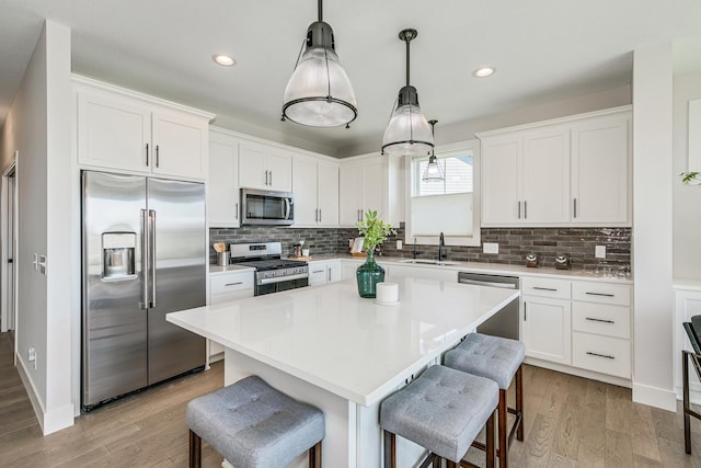 kitchen featuring white cabinetry, hanging light fixtures, and appliances with stainless steel finishes