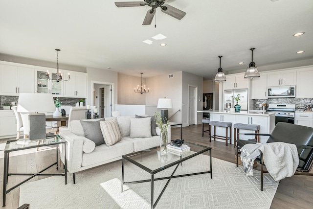 living room with light hardwood / wood-style flooring and ceiling fan with notable chandelier