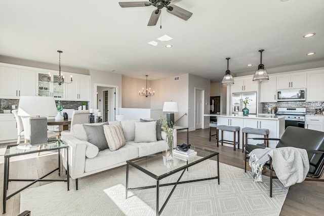 living room featuring ceiling fan with notable chandelier and light hardwood / wood-style floors