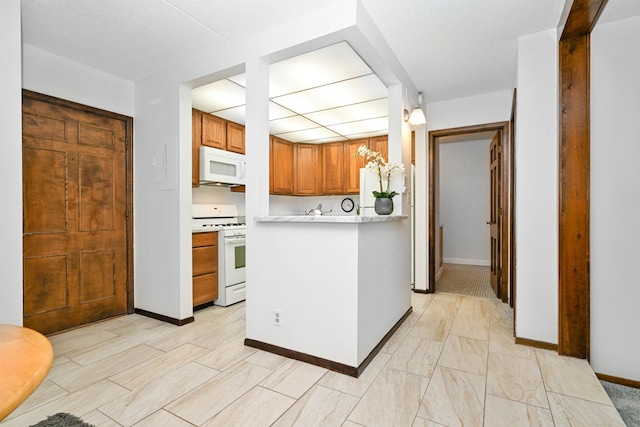 kitchen featuring a textured ceiling, hanging light fixtures, and white appliances