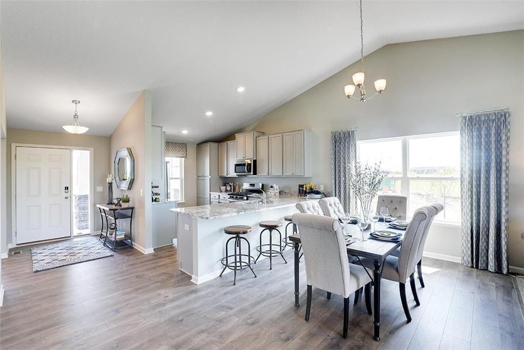 dining area featuring high vaulted ceiling, wood-type flooring, and a chandelier