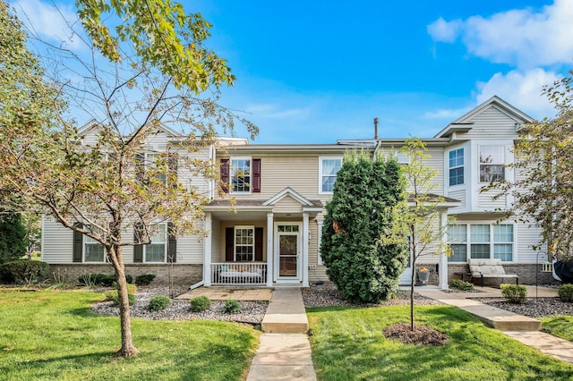 townhome / multi-family property featuring brick siding, a porch, and a front lawn