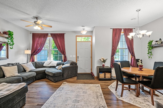 living room featuring a textured ceiling, ceiling fan with notable chandelier, and dark wood-type flooring