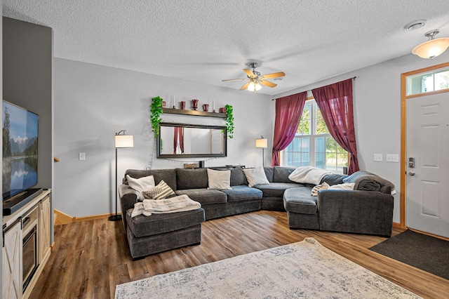 living area with a ceiling fan, wood finished floors, baseboards, and a textured ceiling