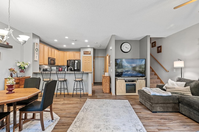 living room featuring stairway, wood finished floors, recessed lighting, a textured ceiling, and a chandelier