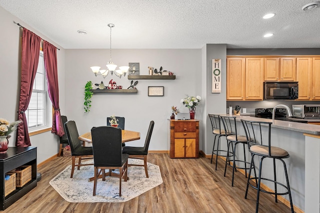 dining area with a toaster, light wood-style floors, baseboards, and a textured ceiling