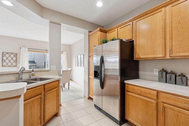 kitchen featuring stainless steel refrigerator with ice dispenser, sink, and light tile patterned floors