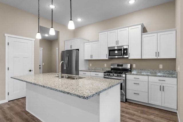 kitchen featuring decorative light fixtures, an island with sink, dark wood-type flooring, stainless steel appliances, and white cabinets