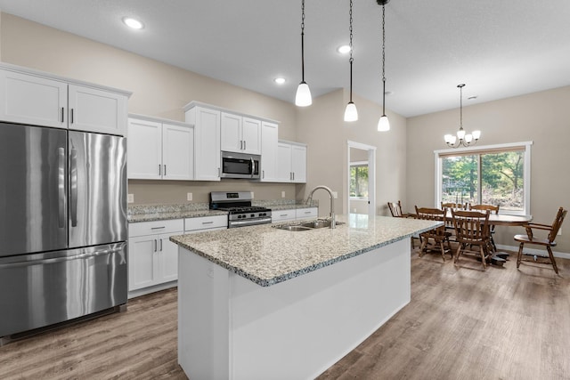 kitchen with appliances with stainless steel finishes, white cabinetry, sink, and pendant lighting