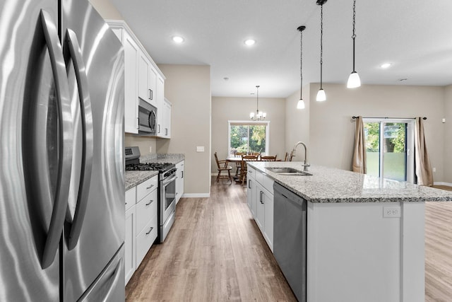 kitchen with pendant lighting, white cabinetry, an island with sink, sink, and appliances with stainless steel finishes