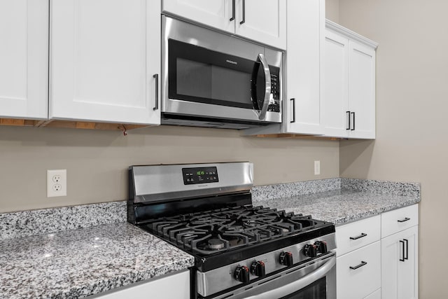 kitchen featuring white cabinetry, stainless steel appliances, and light stone countertops